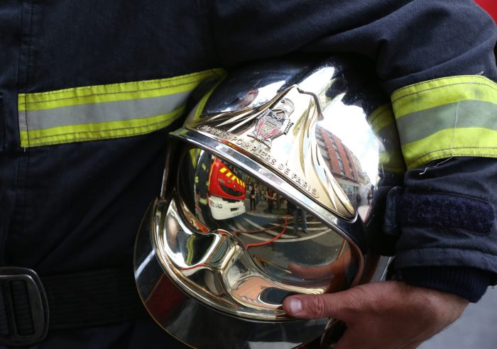 Firefighter carrying his helmet.  France.